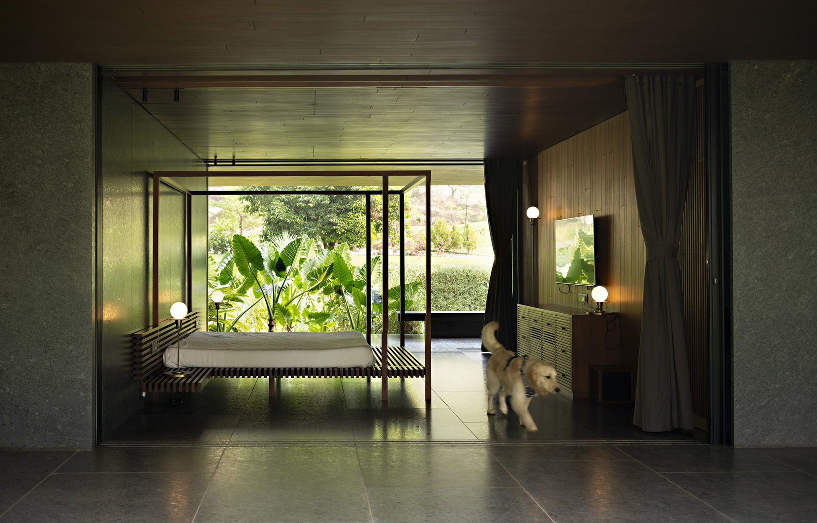 Bed pavilion seen through sliding glass, a dog crossing the granite floor towards the garden