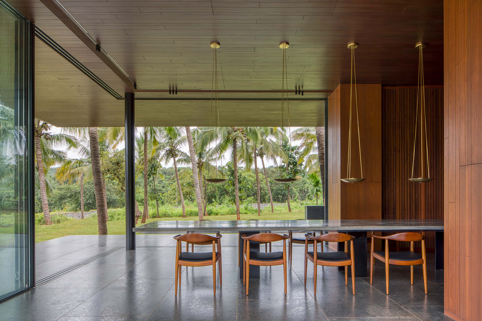 Dining counter and teak chairs with the sliding glass drawn back to the palm grove