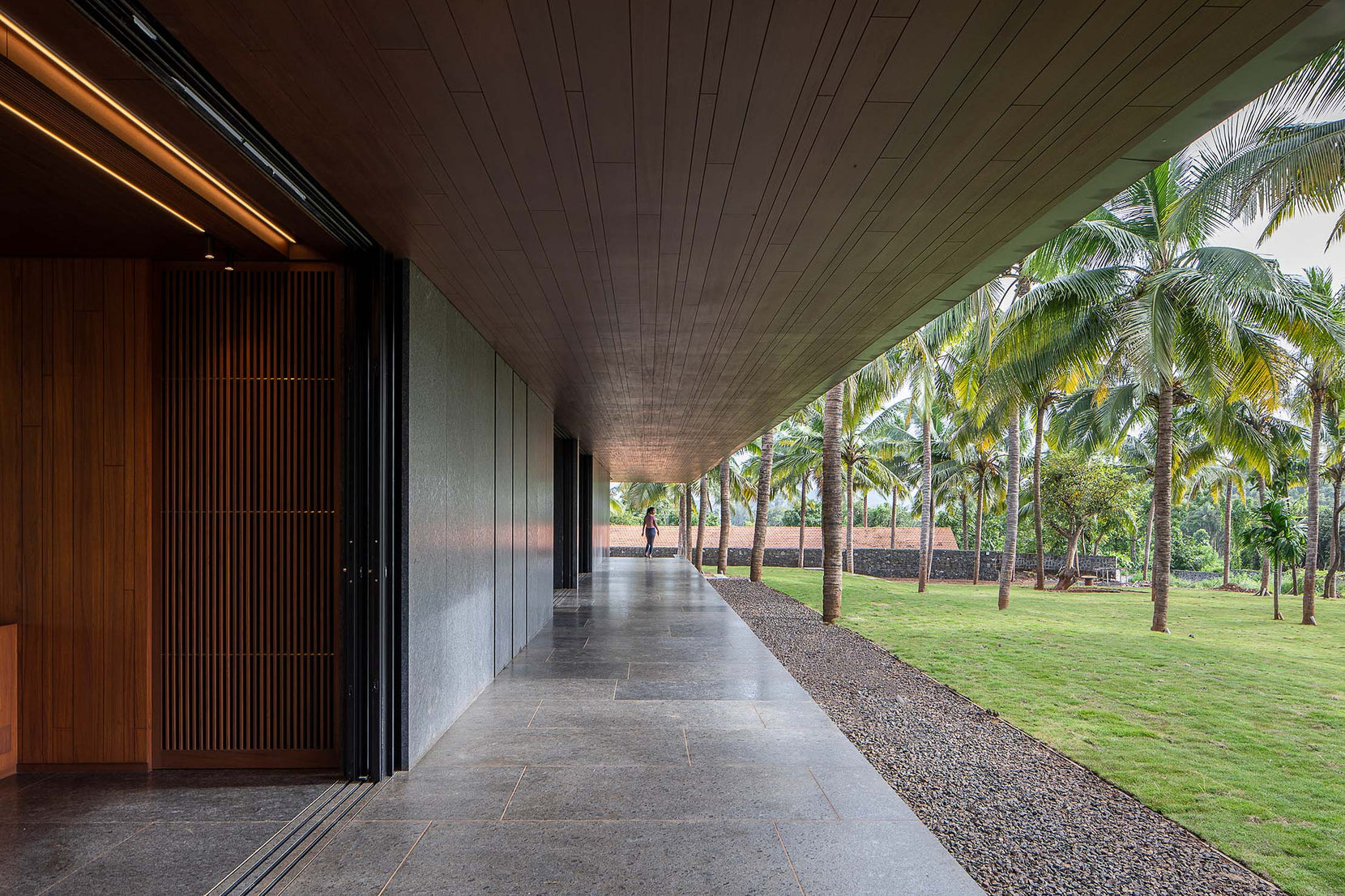 Timber-soffited verandah with a slatted teak screen door, opening to the lawn and palms
