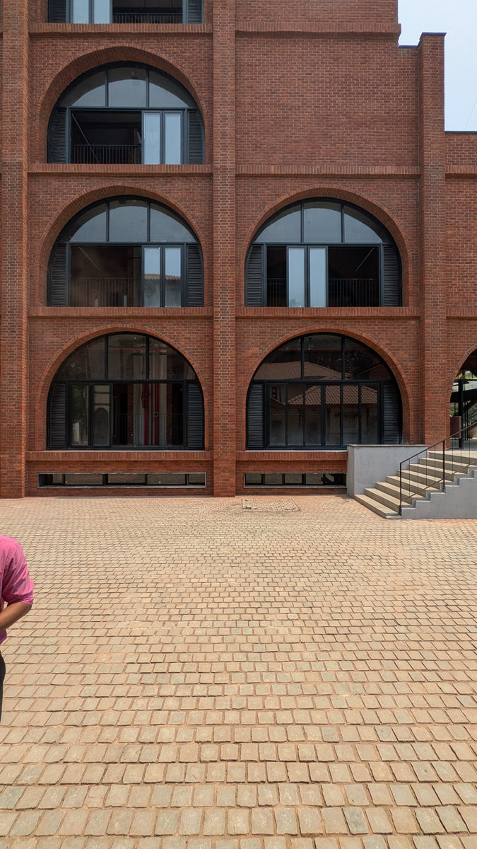 Three tiers of arched glazed openings in brickwork above a stone-block plaza