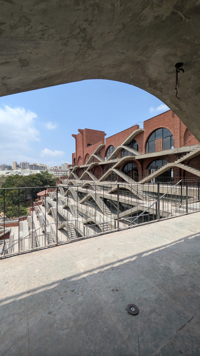 Stair terraces and the city beyond, framed by a board-marked concrete arch