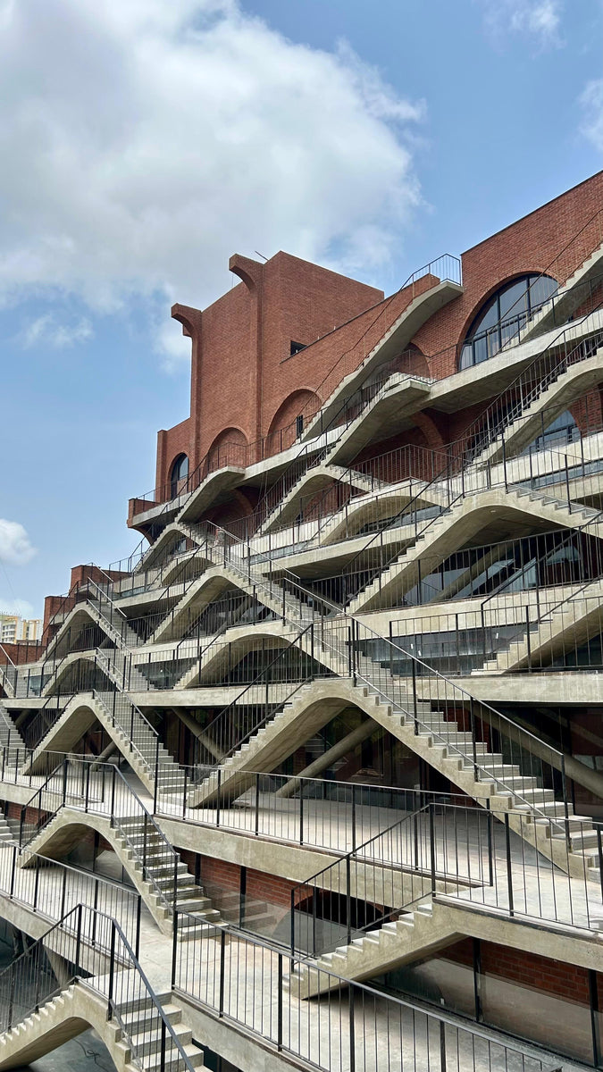 Sanskriti Vihara in Mumbai, its crossing concrete stair flights layered across a brick facade