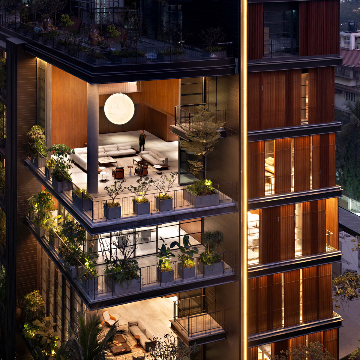 Double-height rooms glowing at dusk, a circular light over the seating and planted terrace edges