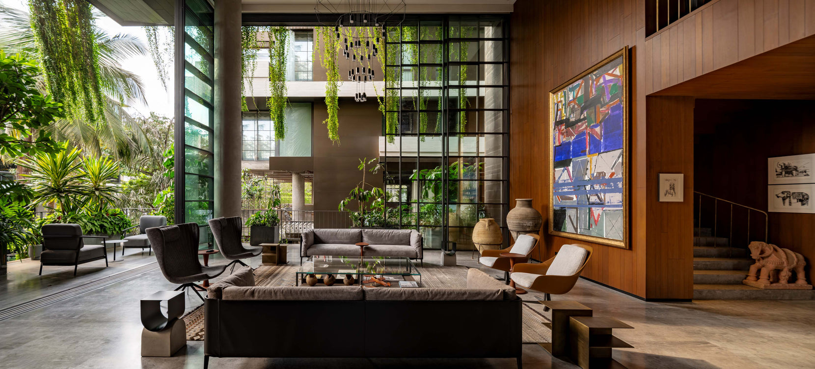 Double-height living room with a large painting, teak wall and glazing onto planted terraces