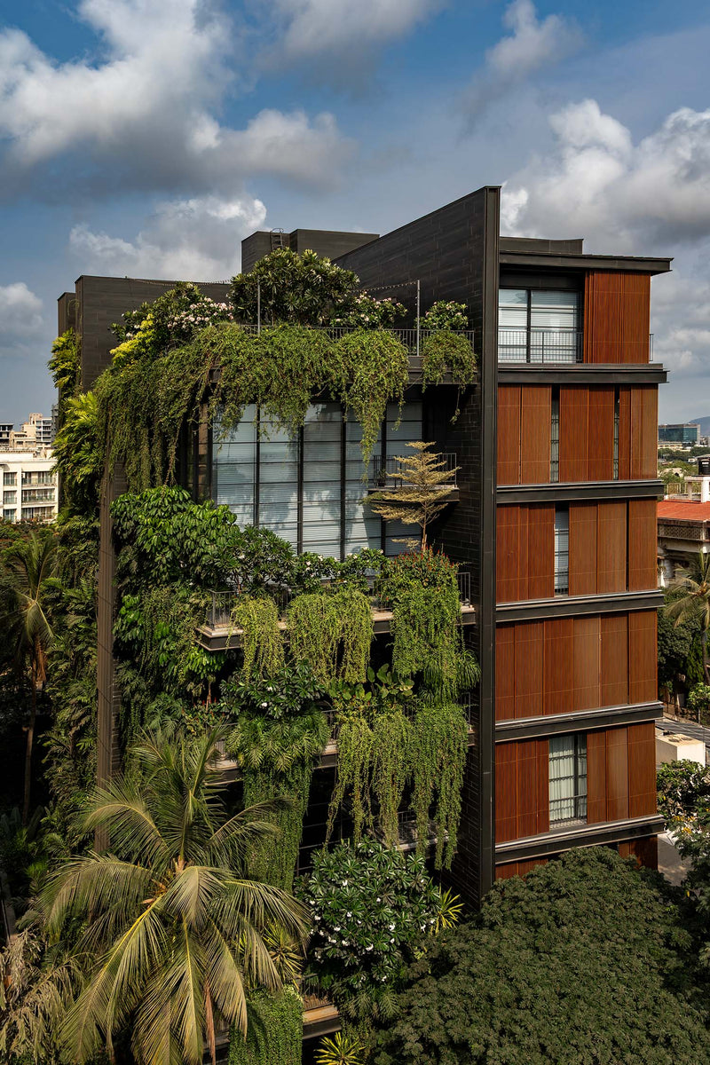 Shiv Kunj in Juhu, its dark stone face hung with cascading planting beside corten-toned panels