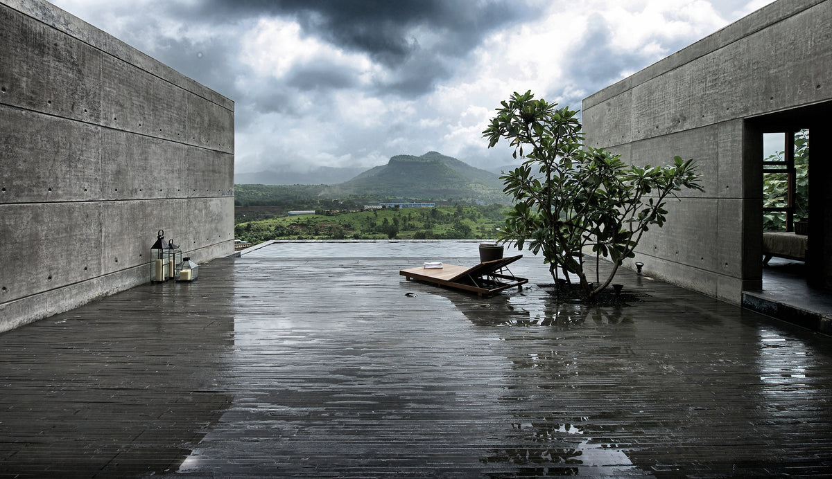 Board-marked concrete terrace at Khopoli running out to an infinity pool under monsoon cloud