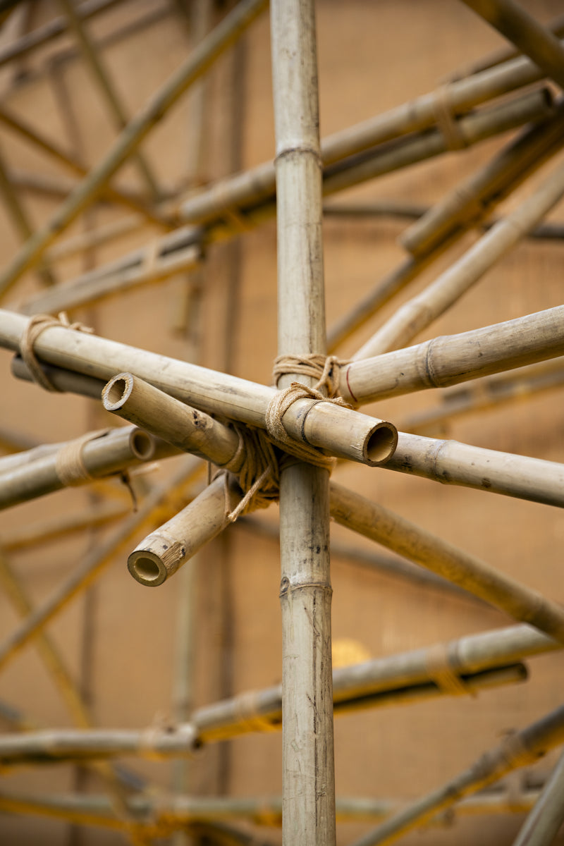 Bamboo members lashed with rope at a radiating joint, the fabric skin blurred behind