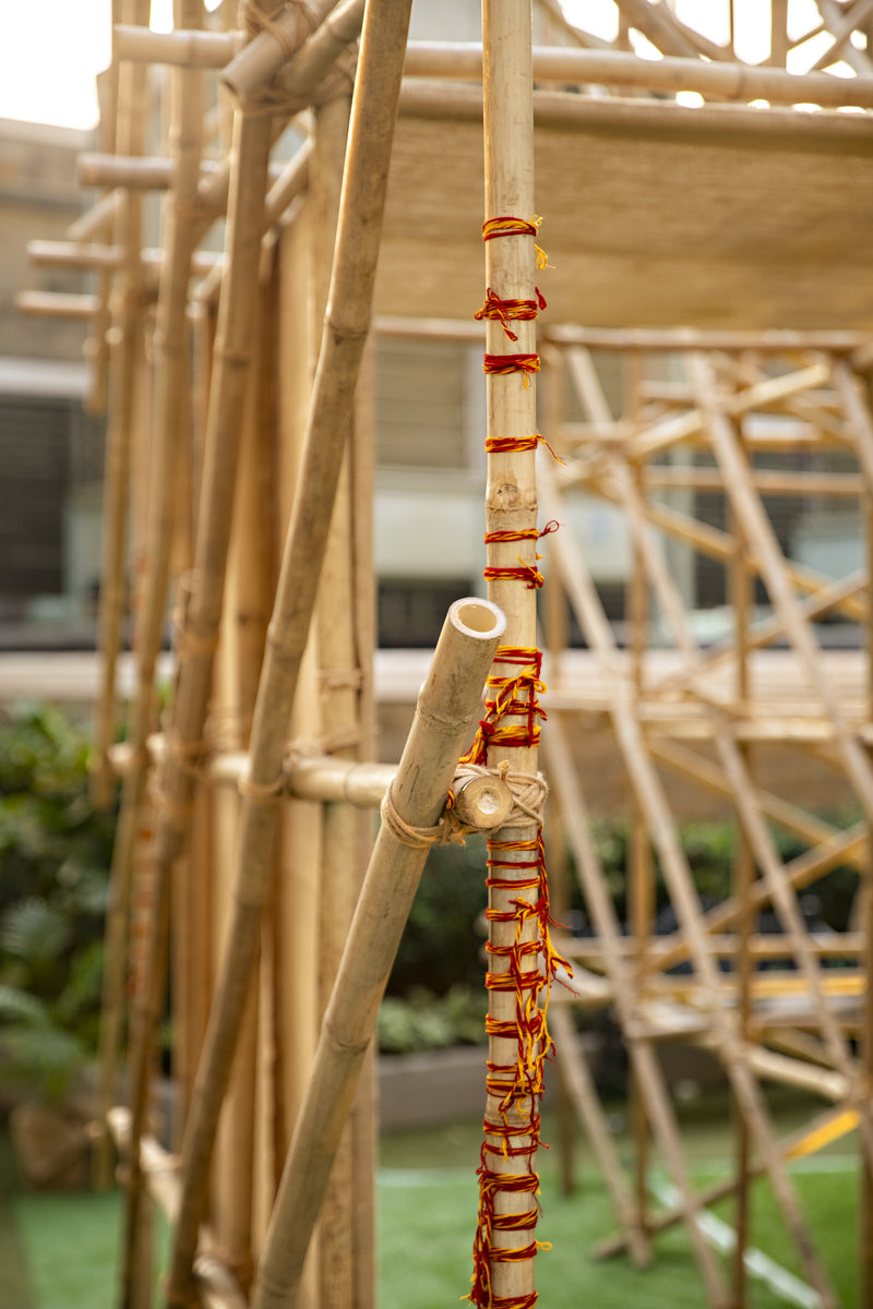 Red and yellow thread bound around a bamboo pole where a cross member meets it
